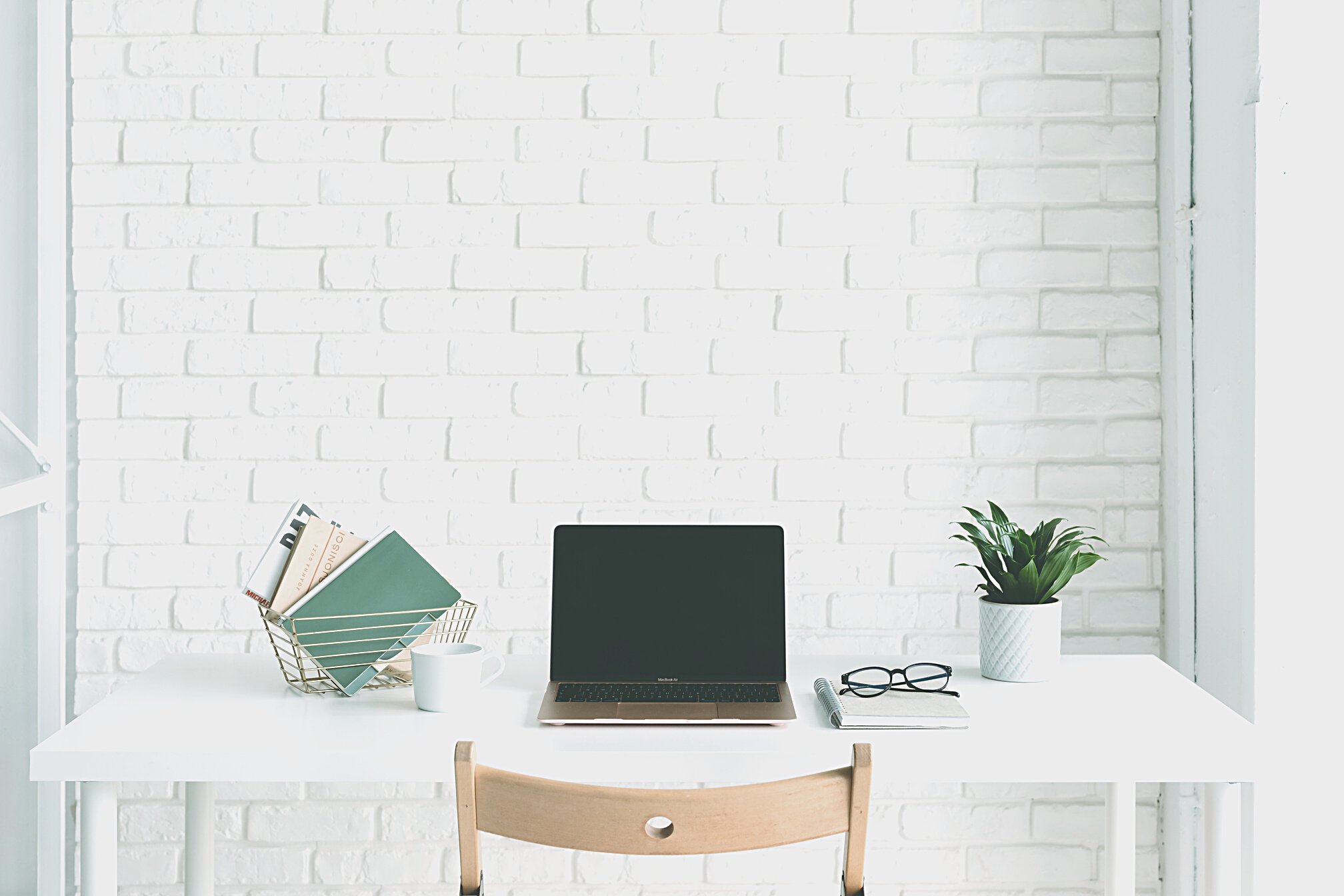 Laptop on White Desk Beside White Brick Wall